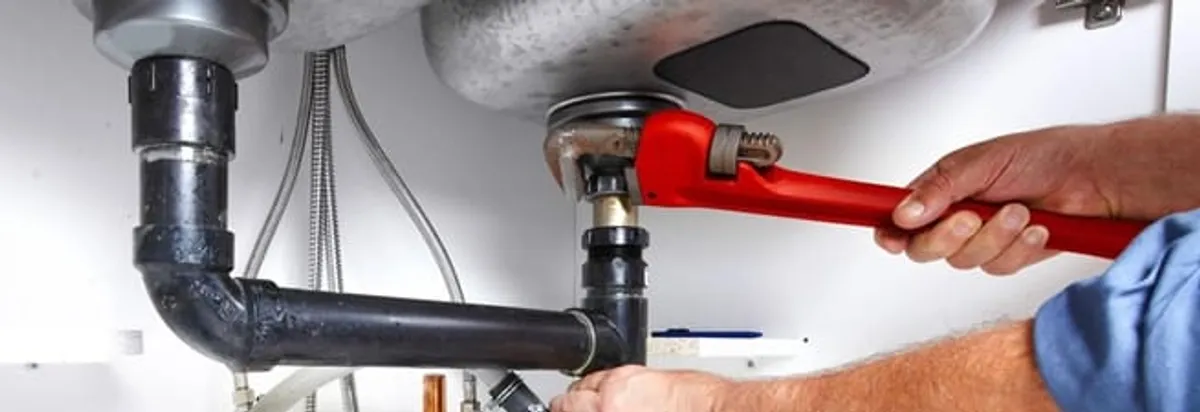 Garbage disposal repair technician tightening the sink drain and disposal connection in Houston, TX