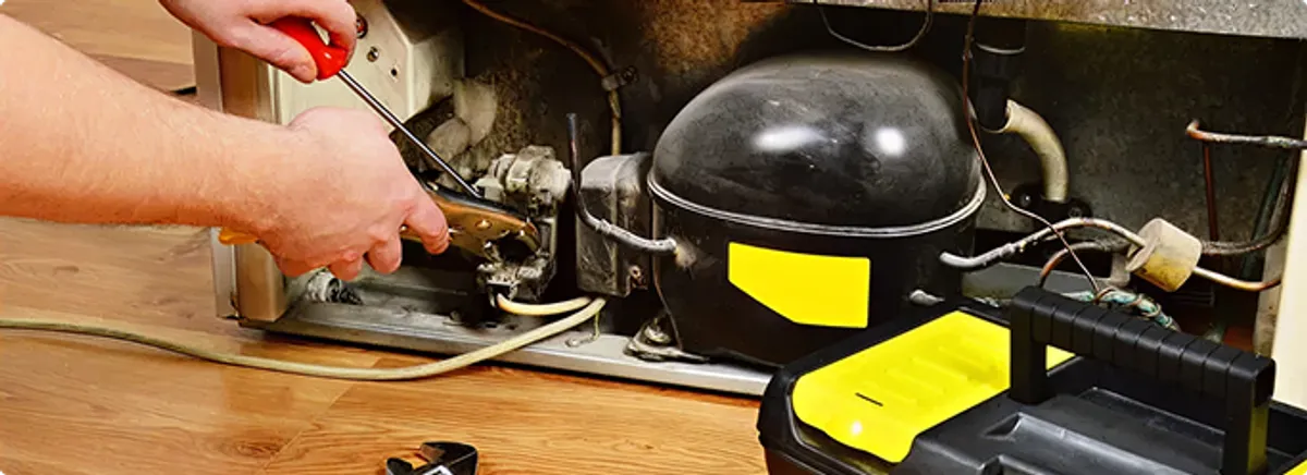 Refrigerator repair technician fixing the compressor and wiring in Houston, TX